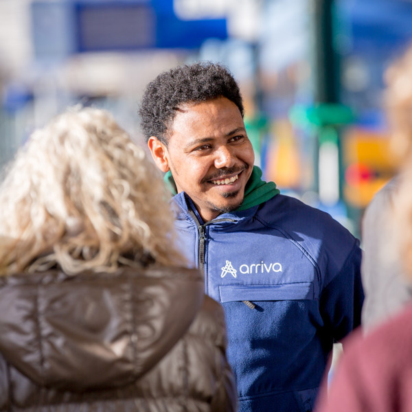Een vrolijke man in een blauw Arriva uniform lacht naar mensen, de zon schijnt. Een vrolijke man in een blauw Arriva uniform lacht naar mensen, de zon schijnt.