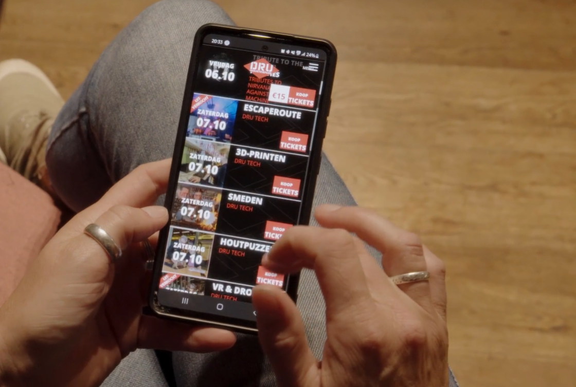 Vrouw met telefoon in haar hand waarop de agenda van het DRU Industriepark staat