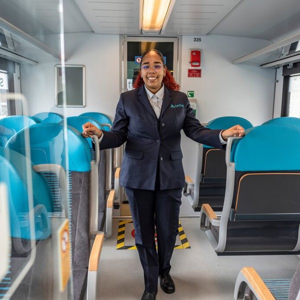 Een vrouwelijke conducteur staat tussen de stoelen in een Arriva trein. Een vrouwelijke conducteur staat tussen de stoelen in een Arriva trein.