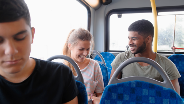 Een man en vrouw lachen samen terwijl ze naast elkaar in de bus zitten. Een man en vrouw lachen samen terwijl ze naast elkaar in de bus zitten.