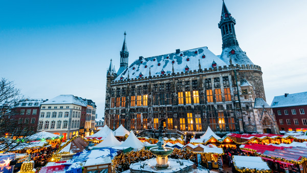 Overzichtsfoto van de kerstmarkt in Aachen, je ziet de aken van de kraampjes met een grote kerk op de achtergrond. Overzichtsfoto van de kerstmarkt in Aachen, je ziet de aken van de kraampjes met een grote kerk op de achtergrond.