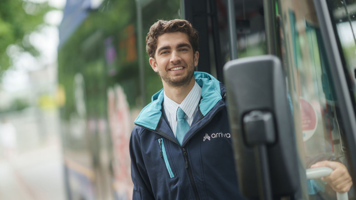 Buschauffeur in zijn Arriva-uniform stapt lachend uit zijn bus. Buschauffeur in zijn Arriva-uniform stapt lachend uit zijn bus.