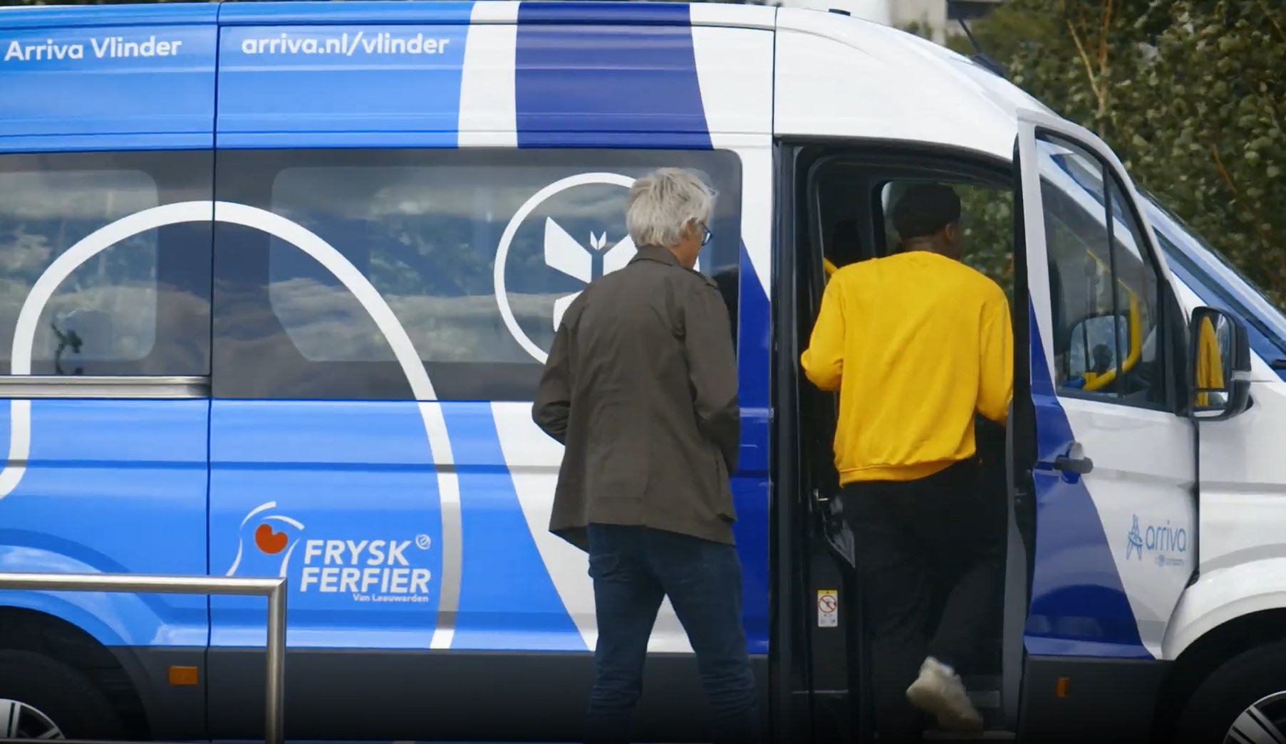 Een blauwwitte buurtbus met daarop arriva.nl/vlinder bezien van de zijkant terwijl mensen instappen.