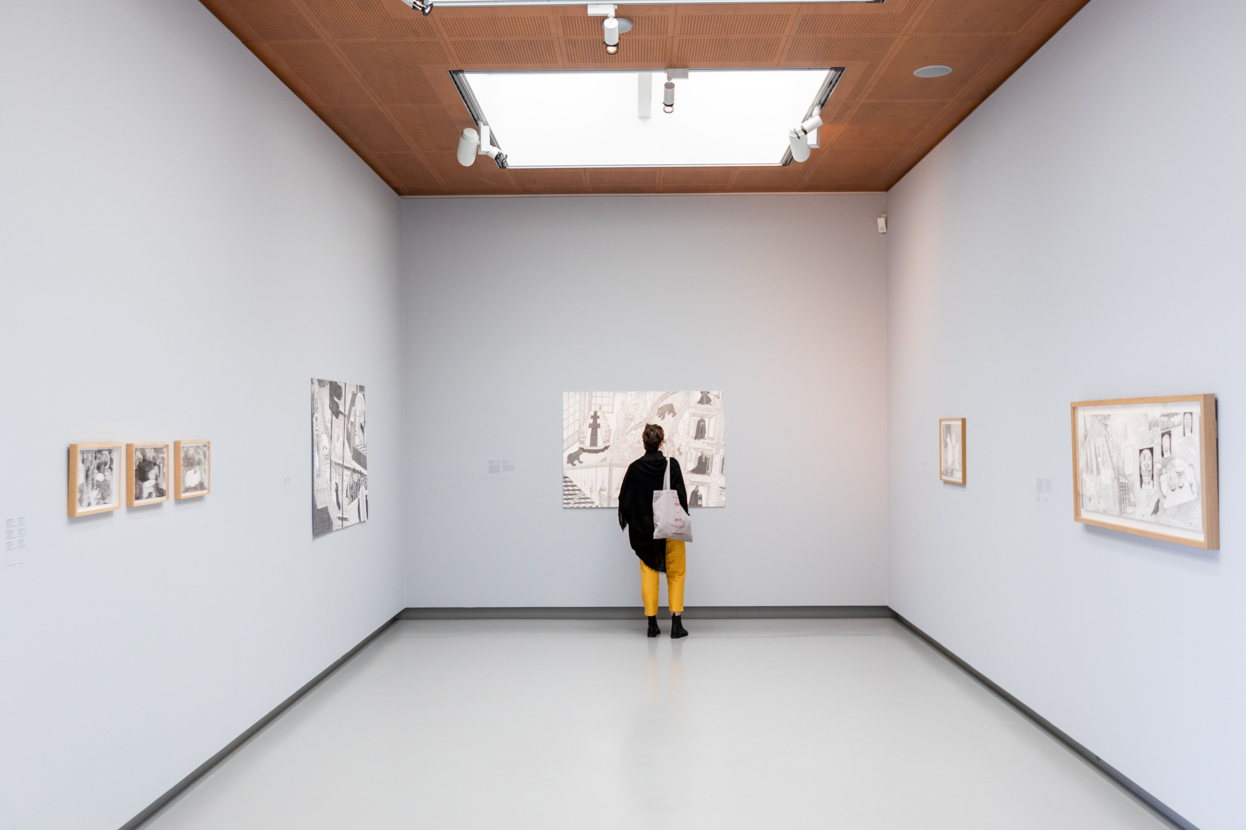 Een vrouwelijke museumbezoeker staat in een lichte zaal van het Fries Museum kunst te bewonderen.