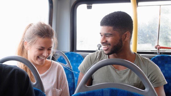 Een man en vrouw lachen samen terwijl ze naast elkaar in een bus van Arriva zitten. Een man en vrouw lachen samen terwijl ze naast elkaar in een bus van Arriva zitten.