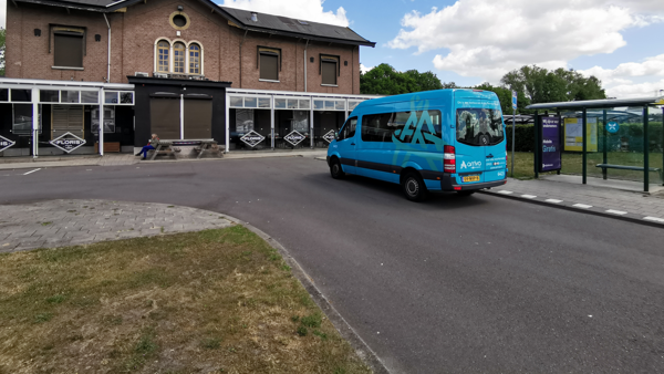 Kleine blauwe buurtbus staat geparkeerd bij een ouderwets, klein station. Kleine blauwe buurtbus staat geparkeerd bij een ouderwets, klein station.