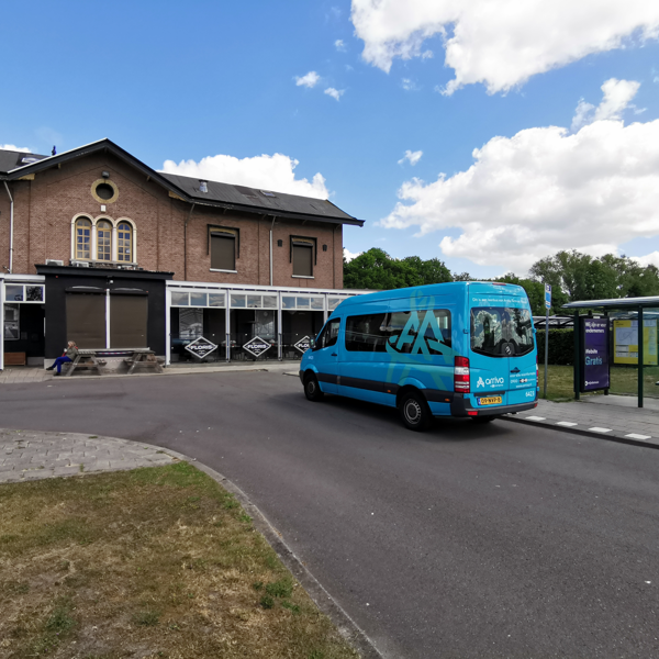 Kleine blauwe buurtbus staat geparkeerd bij een ouderwets, klein station. Kleine blauwe buurtbus staat geparkeerd bij een ouderwets, klein station.