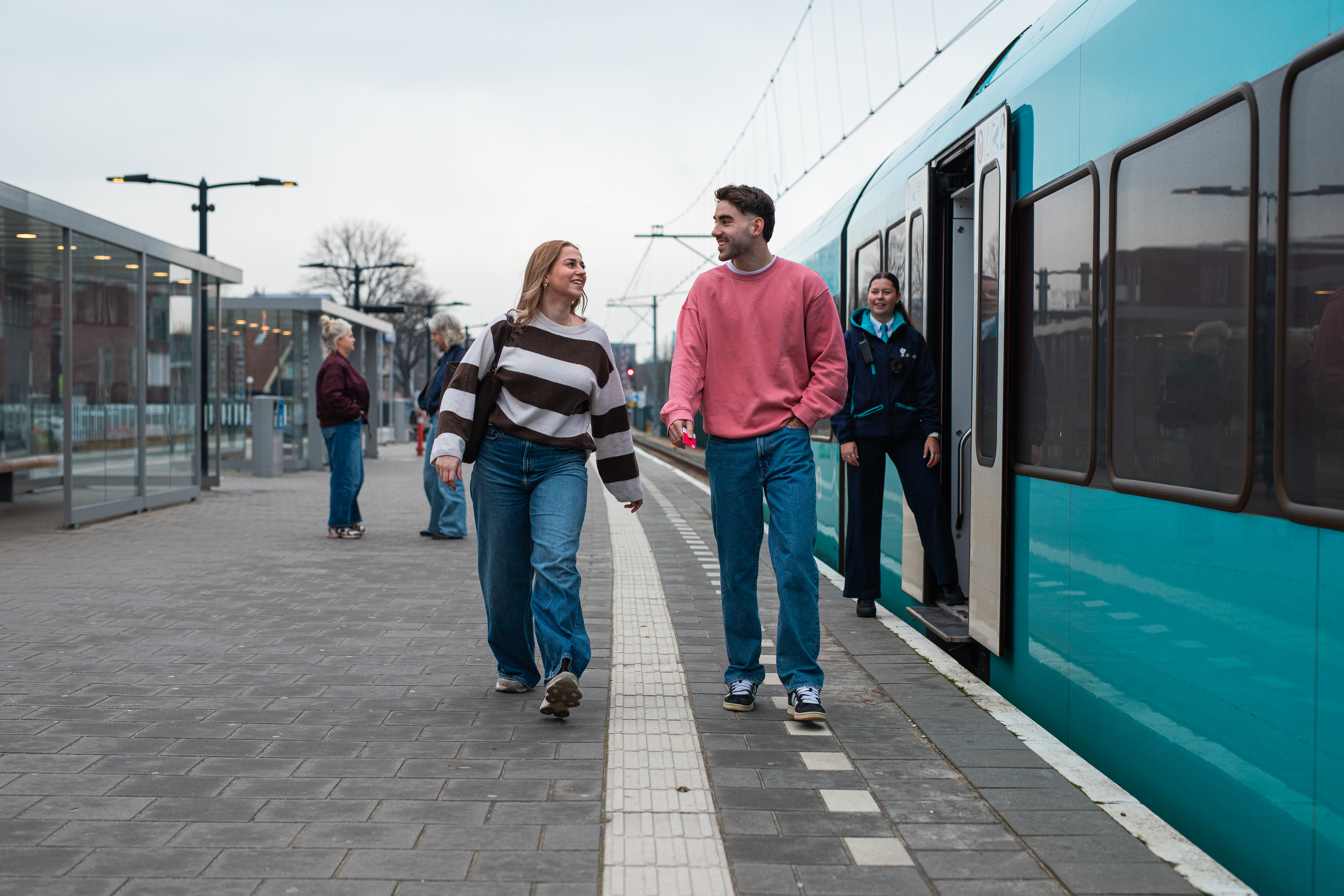 Reizigers lopen langs Arriva trein over perron