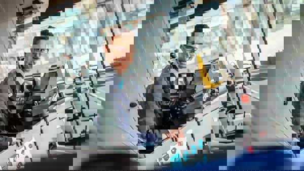 Een mannelijke buschauffeur met een bril zit achter het stuur van een Arriva-bus en kijkt achterom. Een mannelijke buschauffeur met een bril zit achter het stuur van een Arriva-bus en kijkt achterom.