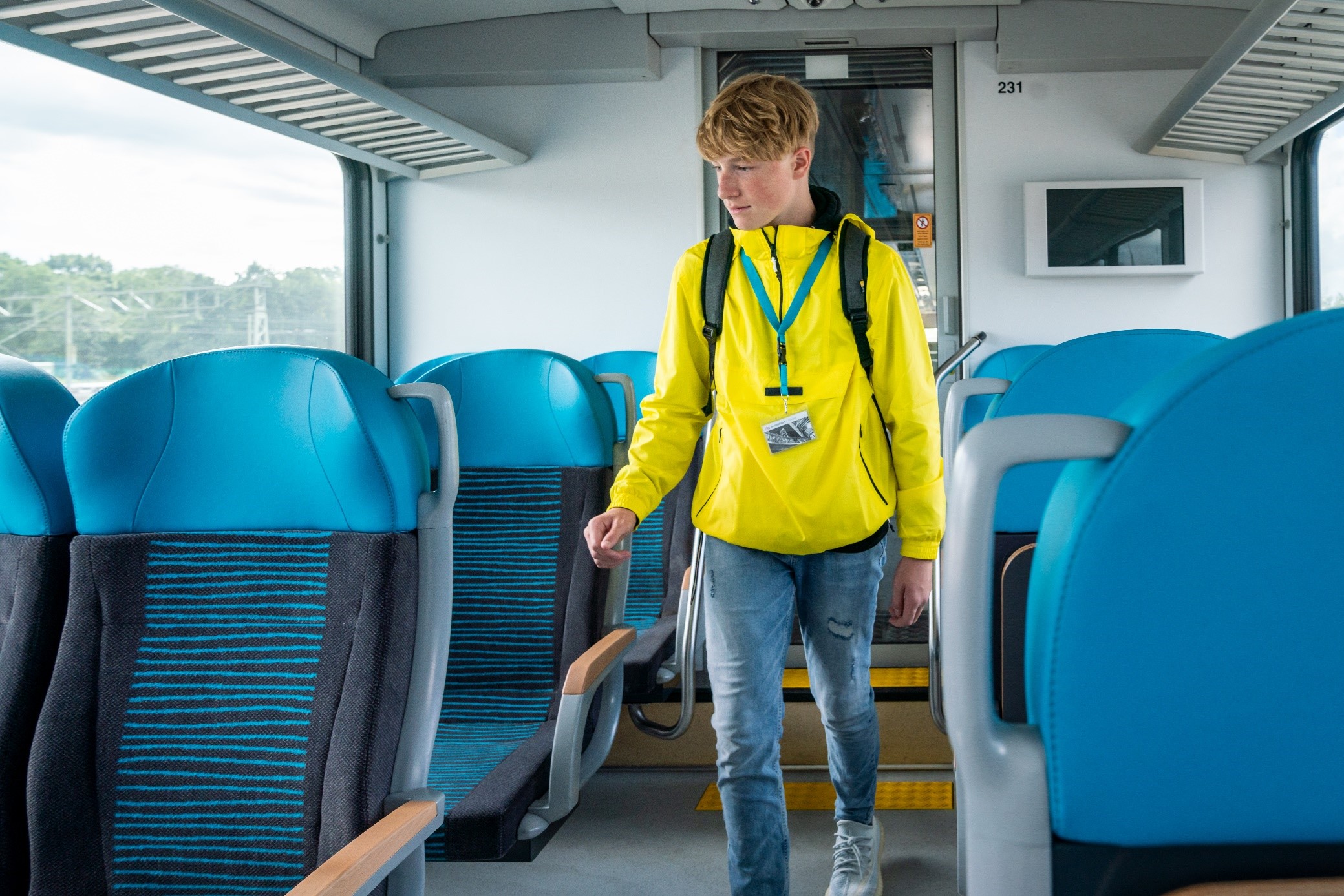 Jongen in gele jas loopt door trein van Arriva.