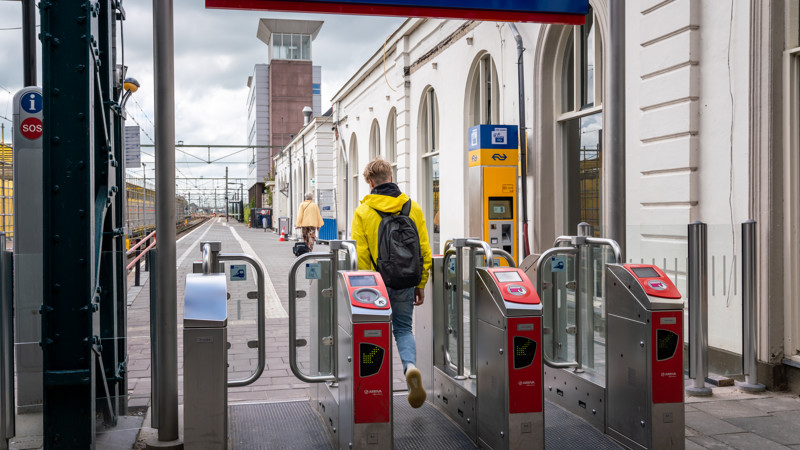 Jonge jongen in felgele jas vanaf de rug gezien is net door incheckpoortjes van Arriva gelopen en loopt het perron op. Jonge jongen in felgele jas vanaf de rug gezien is net door incheckpoortjes van Arriva gelopen en loopt het perron op.