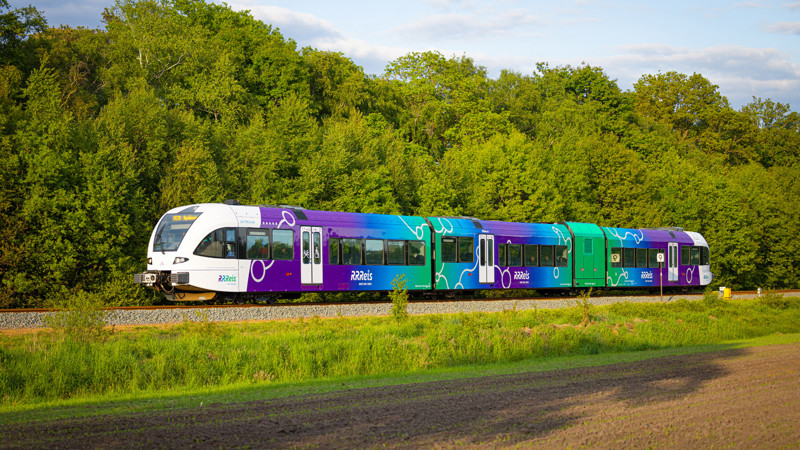 nieuwe trein in de RRReis kleuren op de rails een trein in de RRReiskleuren paars blauw groen op de rails in het Achterhoekse landschap