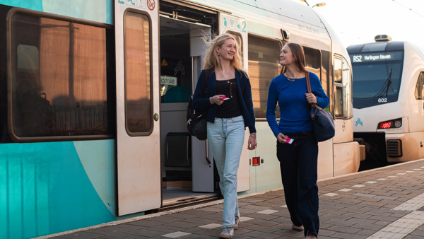Meisjes lopen op perron met op achtergrond Arriva trein Meisjes lopen op perron met op achtergrond Arriva trein