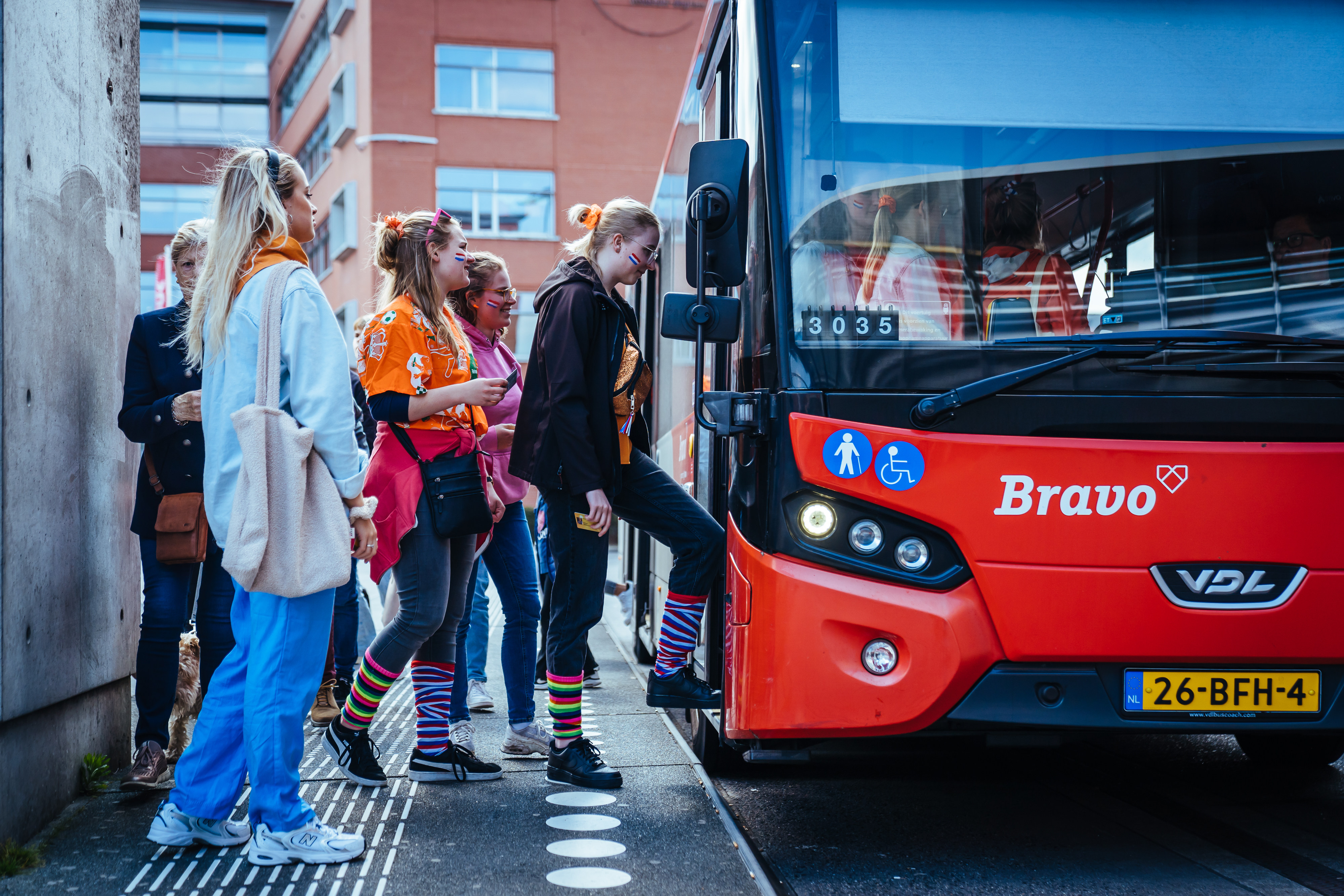 Mensen stappen in de bus tijdens koningsdag