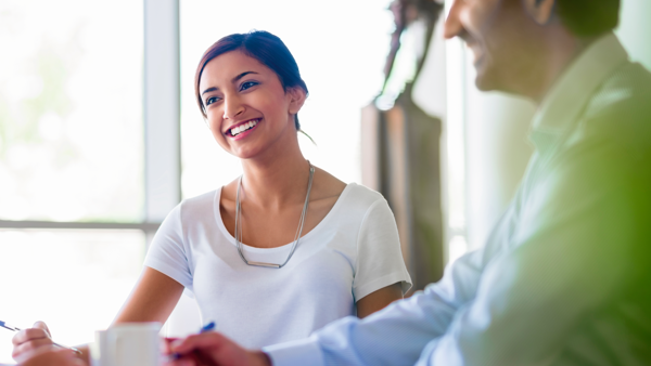 Vrouw en man lachen terwijl ze in het zonlicht aan een tafel zitten met pennen in de hand, waarschijnlijk tijdens een vergadering. Vrouw en man lachen terwijl ze in het zonlicht aan een tafel zitten met pennen in de hand, waarschijnlijk tijdens een vergadering.