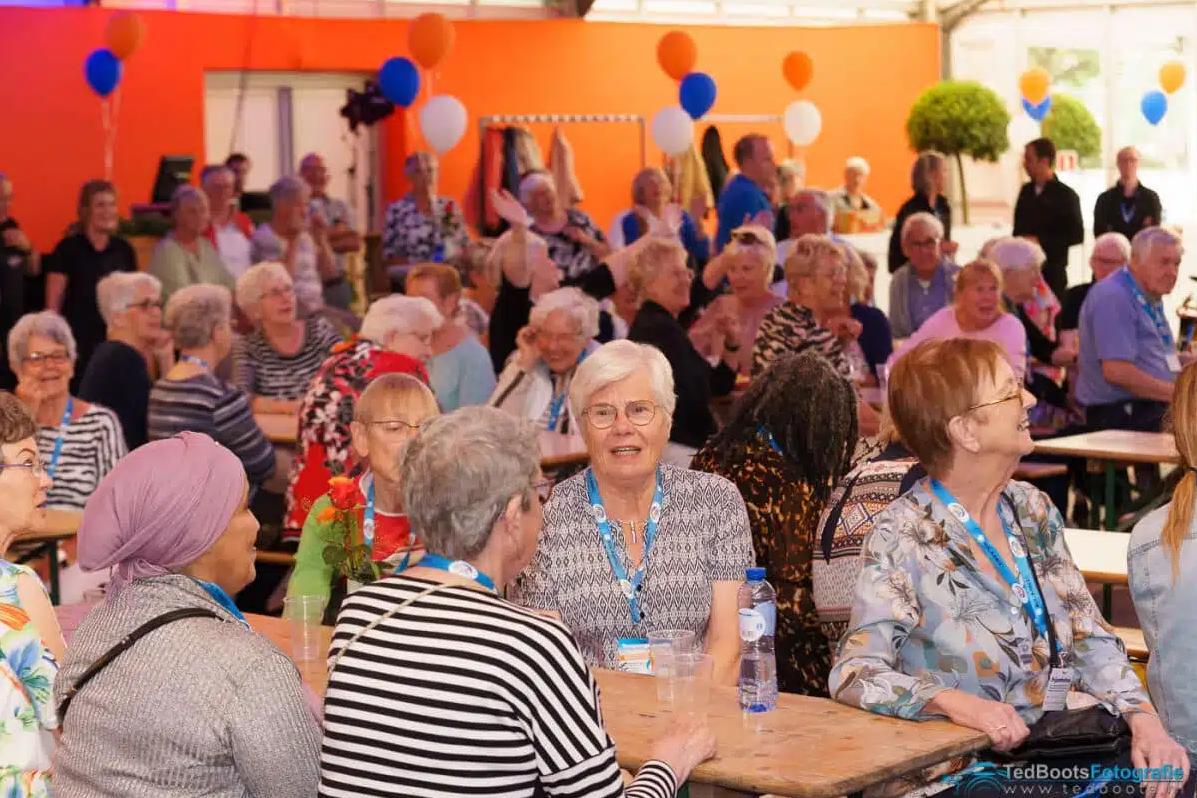 Een groep oudere mensen zit in een tent te lachen en te kletsen tijdens de Venloop.