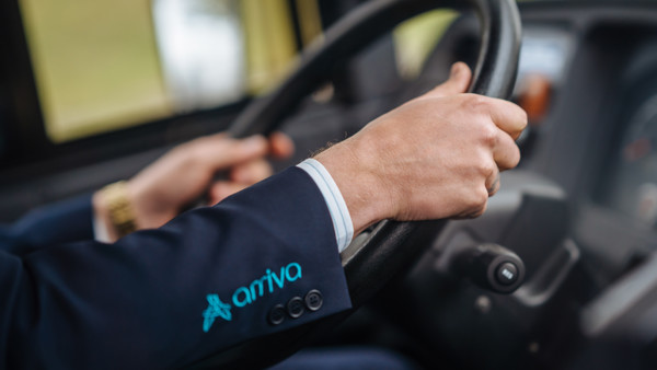 De handen van een buschauffeur aan het stuur van zijn bus, er is nog 'Arriva' te zien op de mouw van zijn jasje. De handen van een buschauffeur aan het stuur van zijn bus, er is nog 'Arriva' te zien op de mouw van zijn jasje.