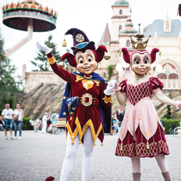 De nar Jokie en een vrouwelijke nar staan samen middenin de Efteling met onder andere de Pagode op de achtergrond. De nar Jokie en een vrouwelijke nar staan samen middenin de Efteling met onder andere de Pagode op de achtergrond.