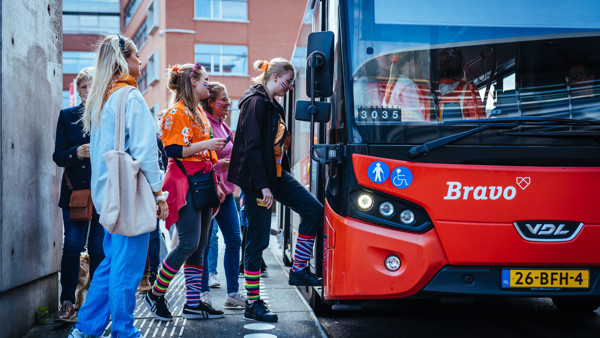 Vrolijk uitgedoste festivalgangers stappen in Bravo-bus tijdens carnaval. Vrolijk uitgedoste festivalgangers stappen in Bravo-bus tijdens carnaval.