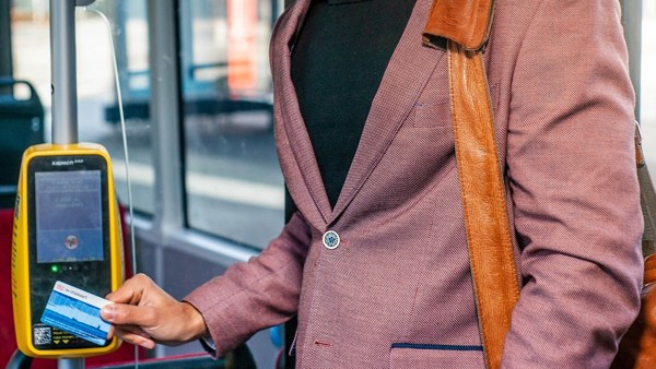Mannelijke reiziger in kleurig pak en met schoudertas checkt in de bus in. Mannelijke reiziger in kleurig pak en met schoudertas checkt in de bus in.